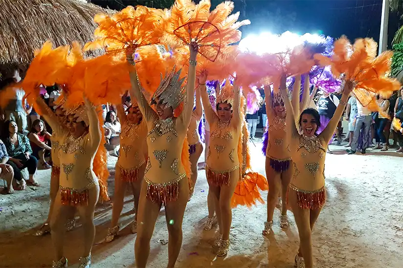 Tanzende Frauengruppe in orangen Gewändern beim Karneval von Holbox