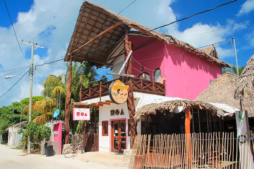 A pink building with a thatched roof showing the NOA Fine Jewelry store in Holbox.