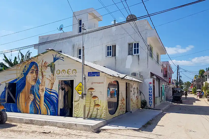 Street with a mural on a building presenting the store Omen in Holbox.