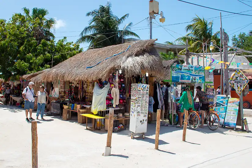 A thatched hut with a sign surrounded by souvenir stalls, the ideal place for Holbox shopping.