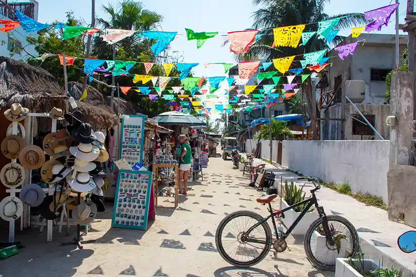 Colorful cloths hang from the buildings of a street with souvenir stalls in Holbox.